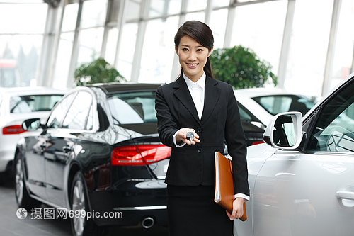 青年女人機(jī)動(dòng)車(chē)站著汽車(chē)銷(xiāo)售人員